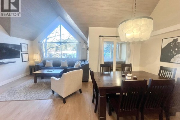Open dining area with table for eight, adjacent to living space and large windows. - Week 9 902-4293 Mountain Square, Whistler