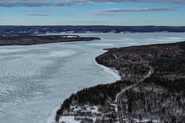 Panoramic view of Lake Ainslie from above, featuring ice-covered water and distant hills. - West Lake Ainslie Road, Lake Ainslie