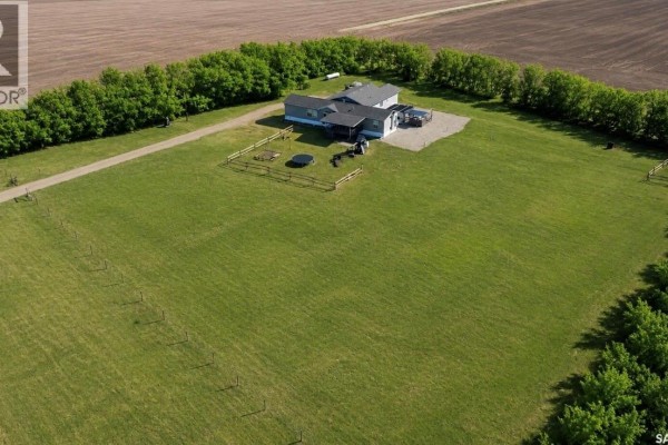 Front view of mobile home with gravel driveway and fenced yard, surrounded by snow. - West Outlook Acreage, Fertile Valley Rm No  285