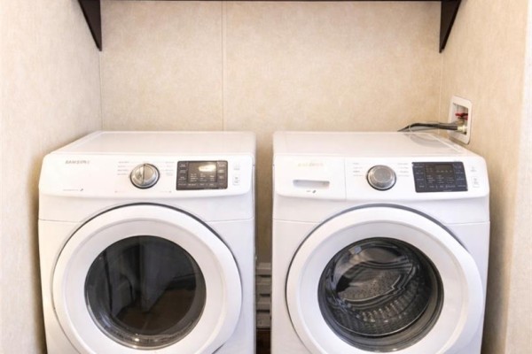 Close-up of white washer and dryer side by side, set against beige wall with minimal decor. - West Outlook Acreage, Fertile Valley Rm No  285
