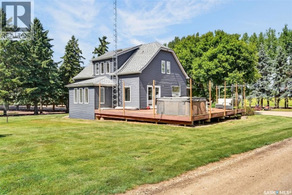 Side view of a dark blue two-story house with a wooden deck and hot tub. - Williams Acreage, Wolverine Rm No  340