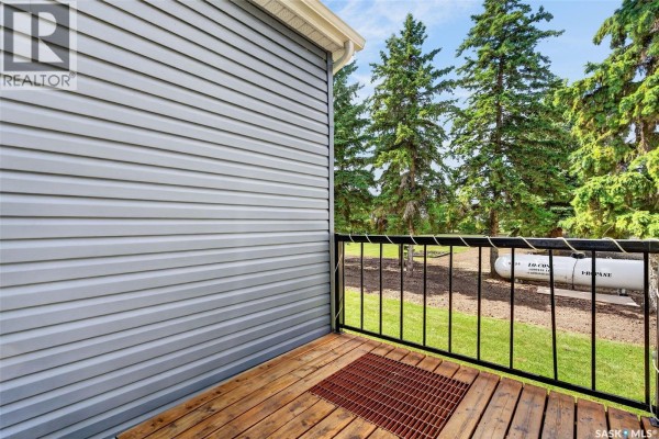 Close-up of a wooden deck with black metal railing and green trees in background. - Williams Acreage, Wolverine Rm No  340