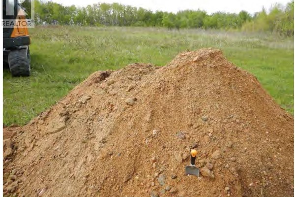 Large pile of aggregate material on the ground with a shovel and green grassy field. - Yorkton Aggregate Quarter Rm 244, Orkney Rm No  244